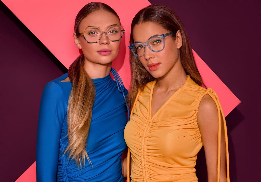 Two models wearing designer glasses against a bold geometric backdrop