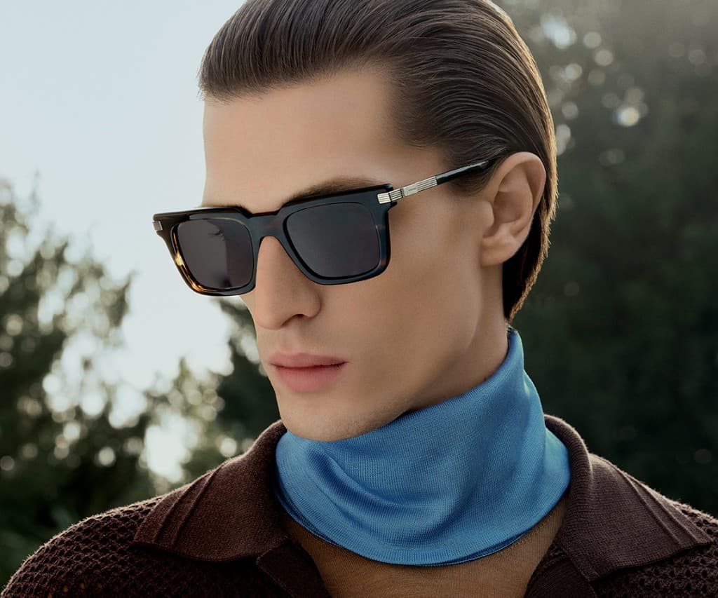 Model wearing tortoiseshell sunglasses and a blue turtleneck outdoors